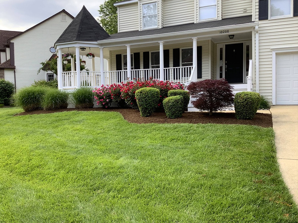 Mowing a green lawn with garden beds